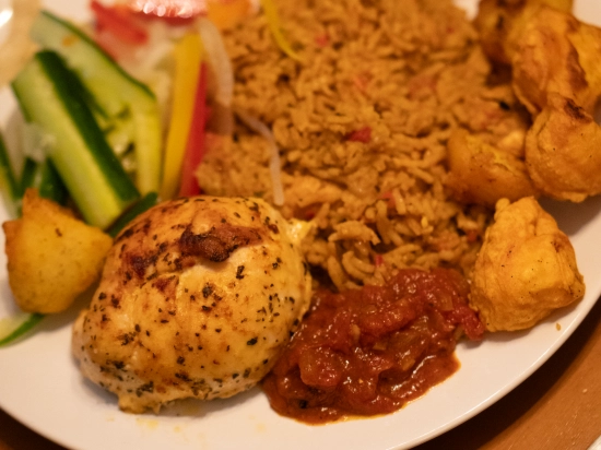 A full plate of pilau rice with salad, baked chicken breast and curry potatoes